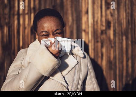 Outdoor portrait of african-american woman. She is blowing her nose. Stock Photo