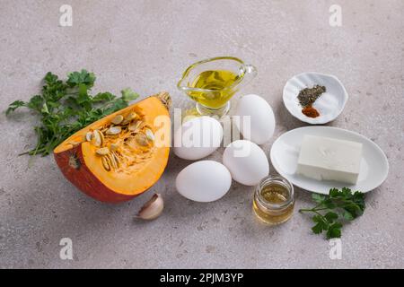 Ingredients for cooking scrambled eggs with pumpkin: fresh eggs, raw pumpkin, feta cheese, olive oil, apple cider vinegar, garlic, herbs and spices on Stock Photo