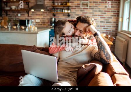 Close up of a Father and daughter using a laptop on a couch in a living room Stock Photo