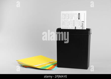 Shredder with sheet of paper and colorful folders on grey background. Space for text Stock Photo