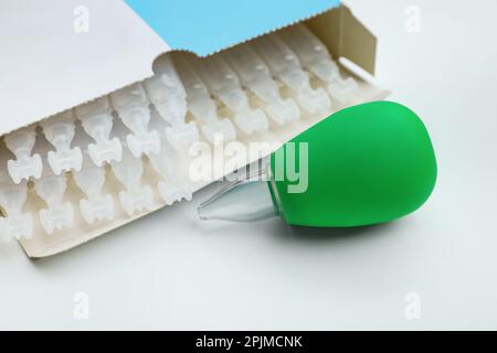 Package with single dose ampoules of sterile isotonic sea water solution and nasal aspirator on white background, closeup Stock Photo