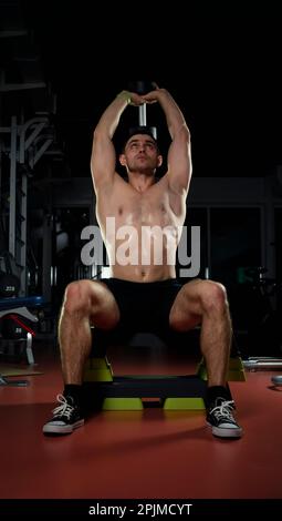 bodybuilder doing heavy weight exercise for biceps with dumbbell. the concept of sports and training. Muscular man with dumbbells in a dark gym Stock Photo