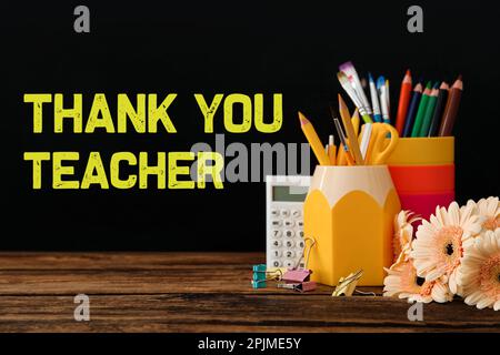 Set of stationery and flowers on wooden table near blackboard with phrase Thank You Teacher Stock Photo