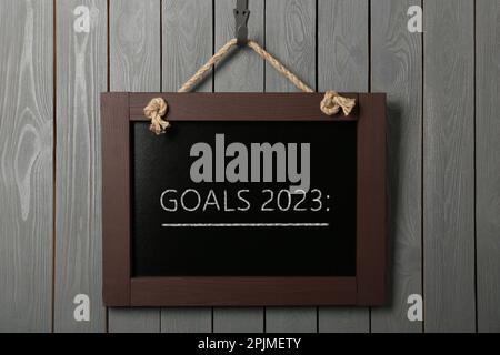Blackboard with phrase GOALS 2023 on hanging on grey wooden background Stock Photo