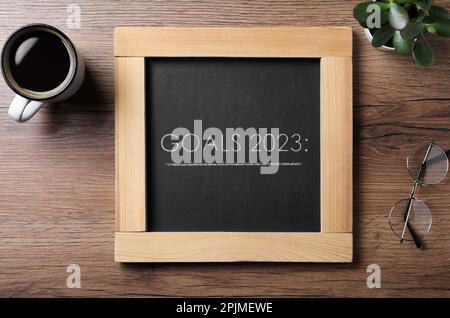 Blackboard with phrase GOALS 2023 on wooden background, flat lay Stock Photo
