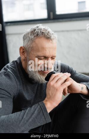 happy middle aged man with tattoos and closed eyes enjoying aroma of puer teastock image 2pjmfh0