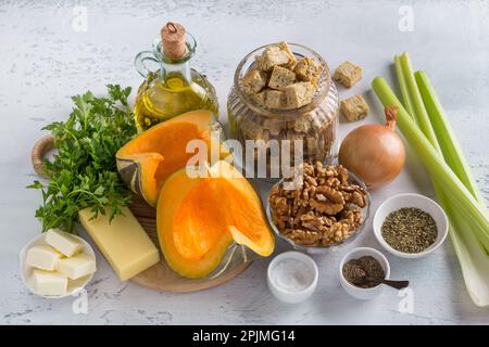 Ingredients for the Vegetarian Stuffing: pumpkin, crunchy croutons, celery, parsley, onion, butter, cheese, olive oil, walnuts and spices on a light g Stock Photo