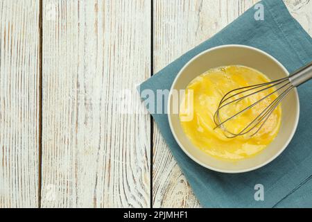 Whisking eggs in bowl on wooden table, top view. Space for text Stock Photo