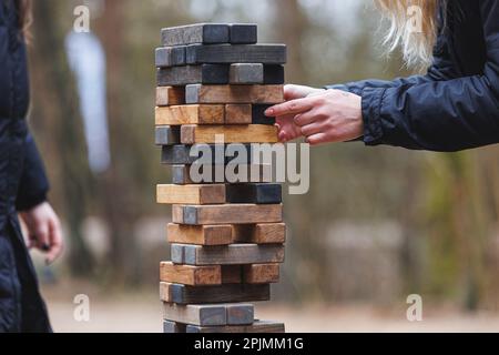 Jenga tower game in nature. Close-up shot of Jenga wooden block game. Concept of risk management. High quality photo Stock Photo