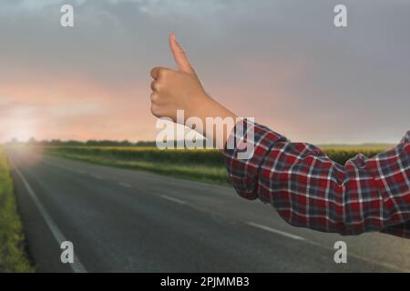 Woman catching car on road, closeup. Hitchhiking trip Stock Photo
