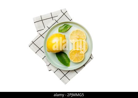Fresh cutted lemon and whole lemons over round plate isolated on white background. Food and drink ingredients preparing. healthy eating theme top view Stock Photo