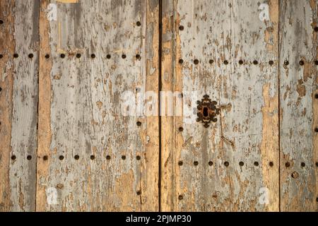 Old and time-worn solid wooden door with decorative metal elements Stock Photo