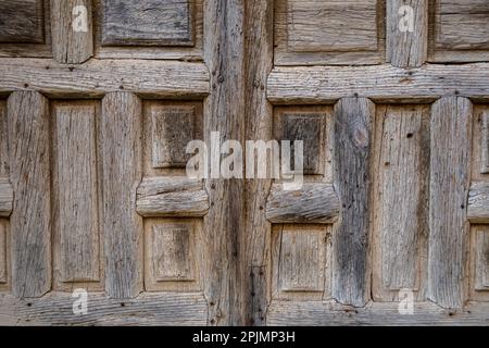 Old and time-worn solid wooden door with decorative metal elements Stock Photo