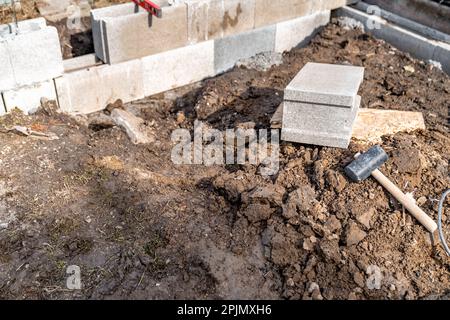 construction of a building made of concrete bricks. using a hammer and spirit level to level the wall Stock Photo