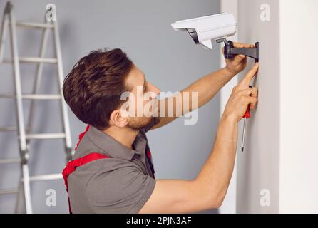 Technician man installing wireless CCTV camera on wall Stock Photo