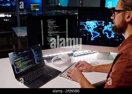 Close-up of young programmer or IT engineer typing on desktop computer keyboard while decoding data with help of new software Stock Photo