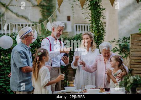 Mature bride and groom toasting with family at wedding reception outside in the backyard. Stock Photo