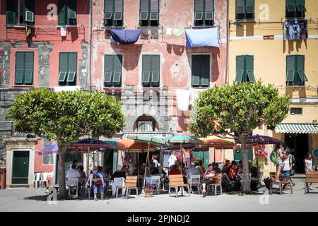 Sheltering from the sun at the seafront Piazza Marconi in the village of Vernazza in the Cinque Terre, Italy. Stock Photo