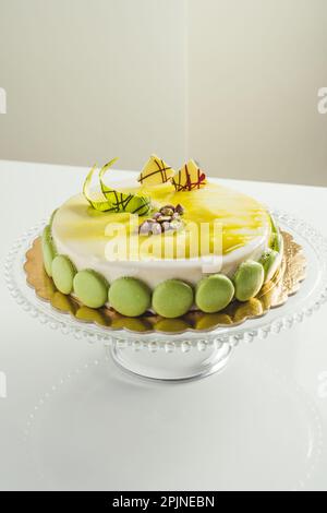 Homemade white glaze cake with pistachio macarons on a glass cake pan Stock Photo