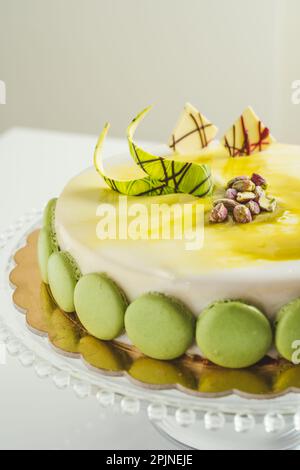 Homemade white glaze cake with pistachio macarons on a glass cake pan Stock Photo