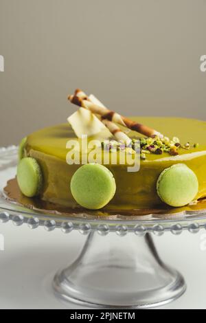 Homemade cake with pistachio macarons and wafers on top in a glass cake pan Stock Photo