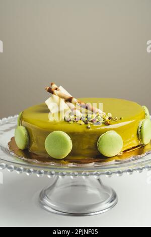 Homemade cake with pistachio macarons and wafers on top in a glass cake pan Stock Photo