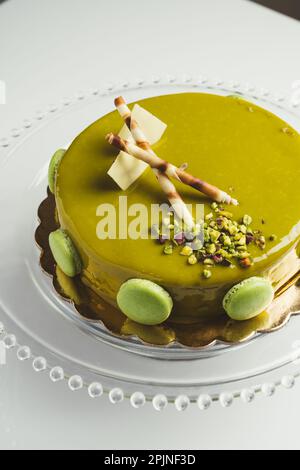 Homemade cake with pistachio macarons and wafers on top in a glass cake pan Stock Photo