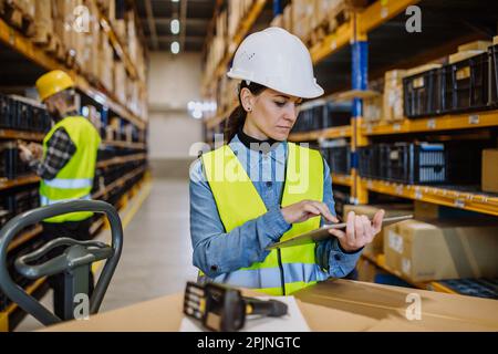 Warehouse workers checking stuff in warehouse with digital system in tablet, holding solar panel. Stock Photo