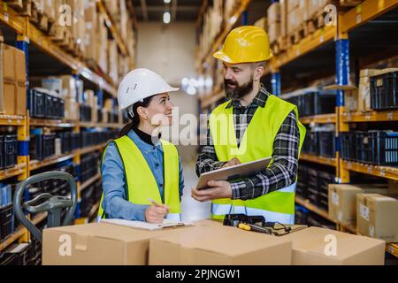 Warehouse workers checking stuff in warehouse with digital system in tablet, holding solar panel. Stock Photo