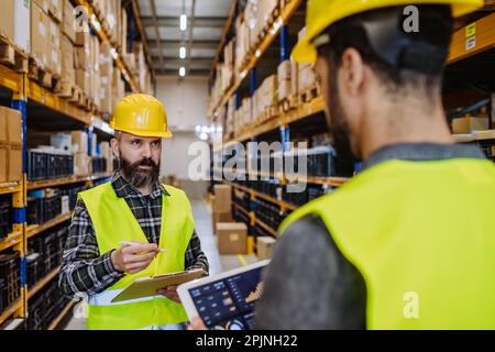 Warehouse workers checking stuff in warehouse with digital system in tablet. Stock Photo