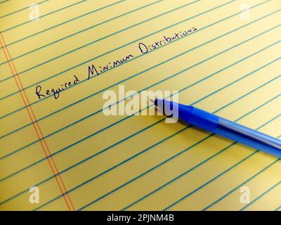 Required minimum distributions from retirement accounts written on yellow legal pad with blue pen notepad as reminder Stock Photo