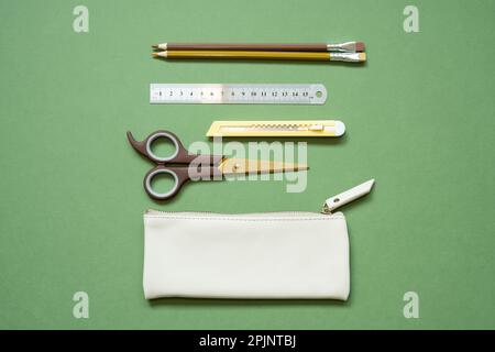 School office writing supplies and pencil case on green desk. top view, copy space Stock Photo