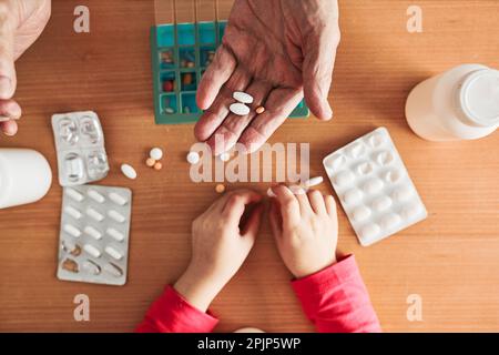Grandchild helping grandfather to organize medication into pill dispenser. Senior man taking pills from box. Healthcare and old age concept with medic Stock Photo