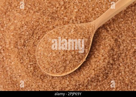 Top view of wooden spoon on granulated brown cane sugar background Stock Photo