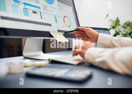 Woman entrepreneur working with data on charts, graphs and diagrams on computer and smartphone. Woman sitting at desk in office Stock Photo