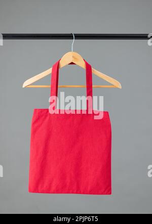 Close up of red canvas bag hanging on wooden clothes hanger with copy space on grey background Stock Photo