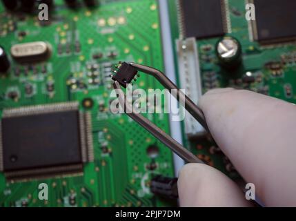 Surface-mount chip removed from the board. Microchip inserting onto an electronic card. Stock Photo
