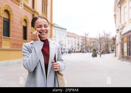 Happy woman standing outdoors and talking on mobile phone Stock Photo