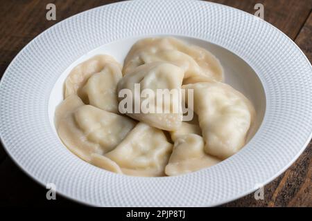 Delicious dumplings stuffed with cottage cheese in a white plate, close up. Ukrainian cuisine Stock Photo