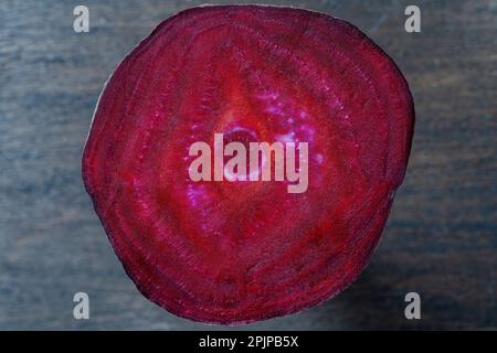 Fresh texture of a slice of beetroot on a wooden background, close up. Surface of red ripe beets. Top view Stock Photo