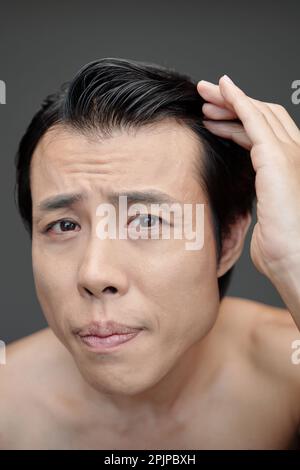 Worrying man checking his hairline, hair loss concept Stock Photo