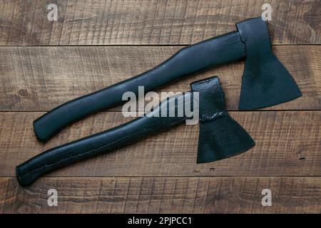 Two black axes on wooden background, top view, close up Stock Photo