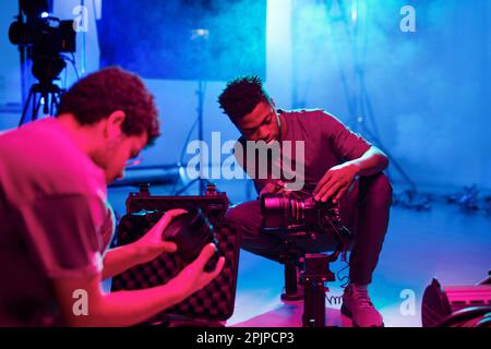 Two professional photographers setting cameras before shooting while working in studio Stock Photo