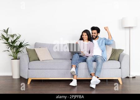 Positive interracial young man and woman using computer at home Stock Photo