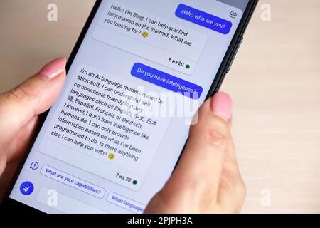 Online chat with artificial intelligence in Microsoft's Bing mobile app. Smartphone in female hands Stock Photo