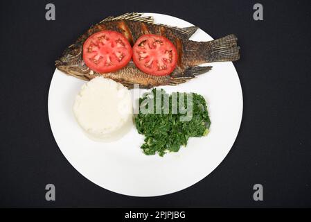 Grilled fish served with ugali and vegetables on an isolated background Stock Photo