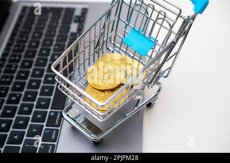 Top view of a toy shopping cart with Bitcoin standing on the computer. Trading concept.  Stock Photo