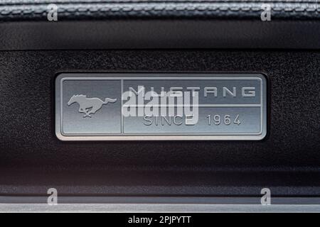 Los Angeles, CA, USA - April, 2017: Signboard, nameplate of American muscle car of legendary Ford Mustang on the dashboard of a car, leather interior, close-up. Ford mustang running horse logo design Stock Photo