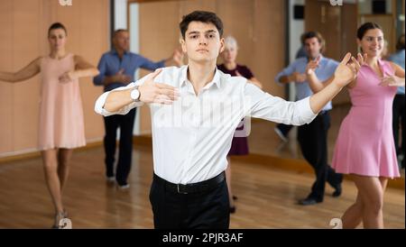 Guy practicing movements of slow dance during group class Stock Photo