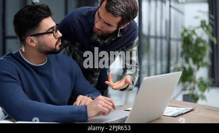 two male colleagues are talking at the table in the office. Stock Photo